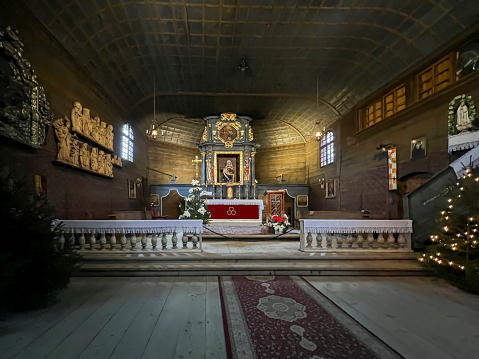 Koszecin, Poland, January 4, 2024: Interior of the old wooden church of the Holy Trinity in Koszecin, Poland during Christmas time. Main altar with pieta.