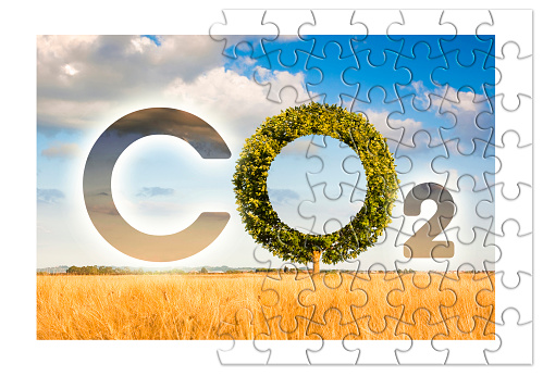 Reduction of the amount of CO2 emissions - concept image in jigsaw puzzle shape with CO2 icon text and tree shape in rural scene.