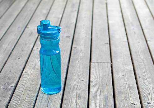 Blue water bottle on wooden background.