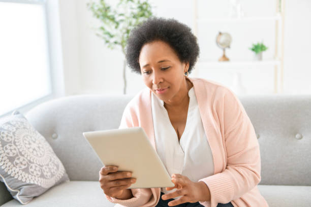istock Black woman using tablet on living room at home 2063686842