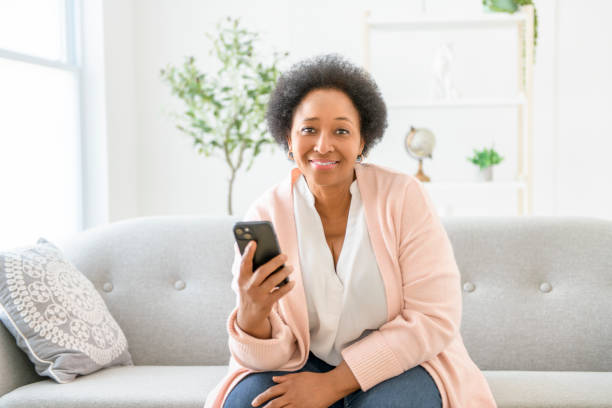 istock Black woman using cellphone on living room at home 2063686863