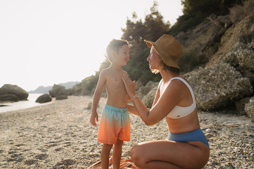 Photo of a mom applying sunscreen lotion on her son