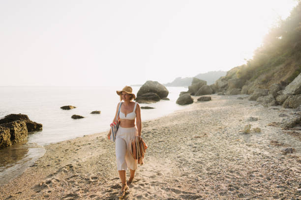 Practicing mindfulness Photo of a mid adult woman walking down the beach: taking care of herself, her mental and physical health walking beach women sadness stock pictures, royalty-free photos & images