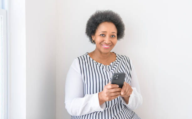 istock senior woman using her cellphone on white room 2063706406
