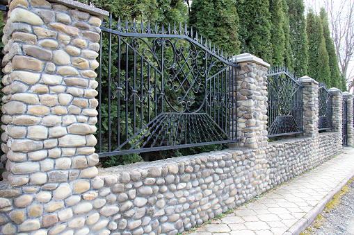entrance of a graveyard with a wrought-iron gate and stone wall detail in gradient back with clipping path