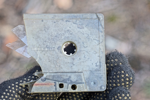 hand holding one piece of old gray broken plastic audio cassette