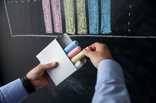 Businessman Choosing The Yellow Chalk From Colored Chalks In White Box