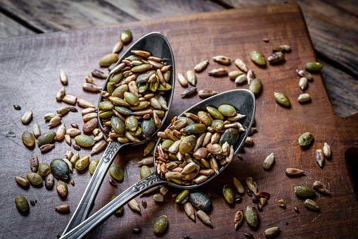 Close up of two spoons filled with roasted sunflower and pumpkin seeds. High resolution 42Mp studio digital capture taken with Sony A7rII and Sony FE 90mm f2.8 macro G OSS lens