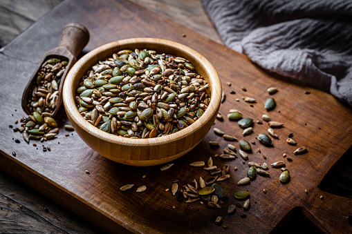 Mixture of roasted sunflower and pumpkin seeds in a wooden bowl. High resolution 42Mp studio digital capture taken with Sony A7rII and Sony FE 90mm f2.8 macro G OSS lens