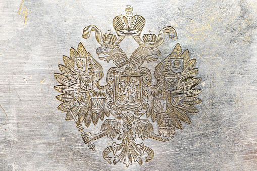 Coat of arms of the Russian Empire, double-headed eagle engraved on a scratched metal plate, macro photo
