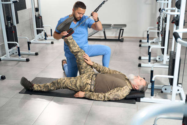 un massaggiatore esperto aiuta un paziente militare con la riabilitazione - men male military beautiful foto e immagini stock