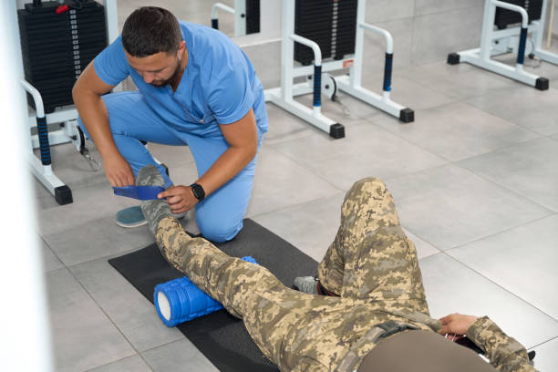il riabilitatore maschio lavora con un paziente militare in palestra - men male military beautiful foto e immagini stock