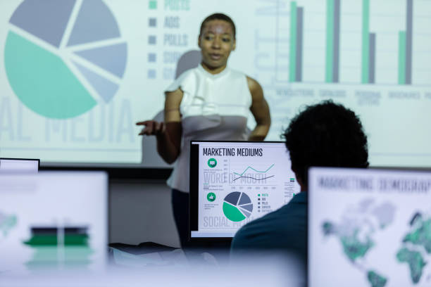 istock Unrecognizable marketing intern looks at his computer while listening to the speaker at the front of the class 2063789112