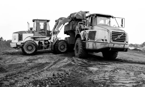 Wheel loader silhouette are digging soil with bucket lift up in the construction site on white  background