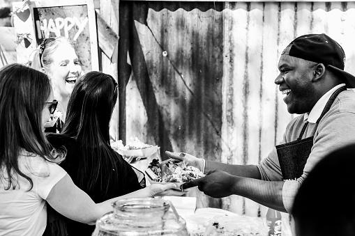 Johannesburg, South Africa – January 02, 2024: A man serving food to women at an outdoor gathering