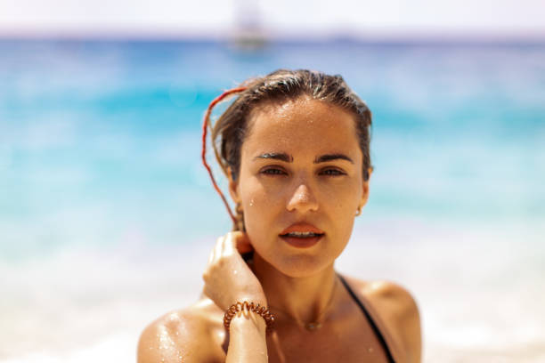 Portrait of gorgeous young woman enjoying alone on the beach. She looks beautiful and carefree in black bikini.