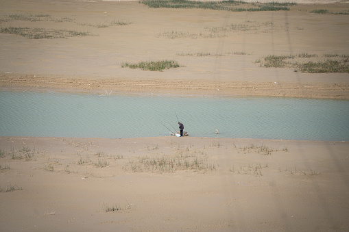 Man fishing in dry river