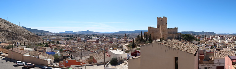 Villena, Alicante, Spain, March 6, 2024: Panoramic view of the town of Villena and the medieval castle of Arab origin of the Atalaya with the mountains in the background. Villena, Alicante, Spain