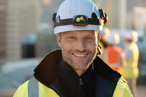 Portrait, man or hard hat for construction, architecture or project management of real estate. Smile, architect or engineer with helmet for safety or maintenance on building, industrial and property