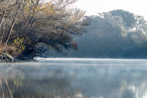 A serene river flows gently, enveloped in a mysterious mist that dances over its waters, creating an ethereal and tranquil landscape. The mist blurs the contours, adding a touch of mystery to the scene.
River Duero as it passes through Tordesillas Valladolid - Spain