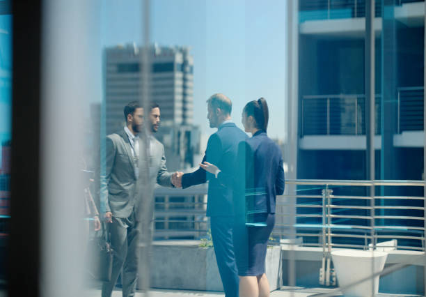 Business people, team and handshake in rooftop meeting for b2b project, networking and partnership in city. Collaboration, employees and shaking hands on office building for welcome and onboarding