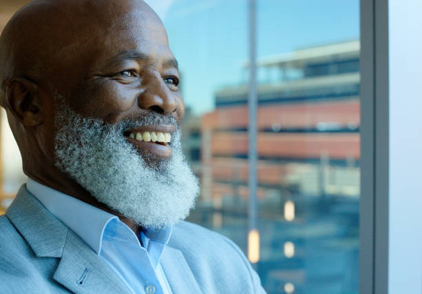 istock Thinking, happy and business black man by window with ideas, brainstorming project and planning. Corporate worker, manager and senior person for strategy, problem solving or solution in modern office 2063868546