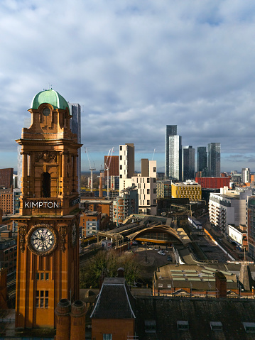 An aerial photograph of downtown Manchester in Northwest England. The photograph shows a Victorian Clock Tower set against a modern urban skyline with skyscrapers. Oxford Road Train Station can be seen in between the clock tower and the skyscrapers