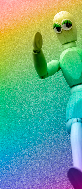 Wooden mannequin with funny eyes on a multicolored background with space for copy.