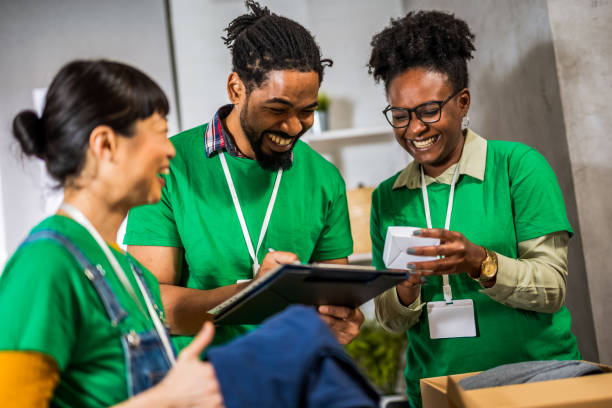 istock Smiling activists putting second-hand clothes in cardboard boxes for donation. 2063926163