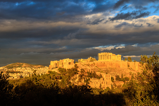 View of the Acropolis Hill, crowned with Parthenon during evening golden hour from the Philopappos Hill in Athens, Greece