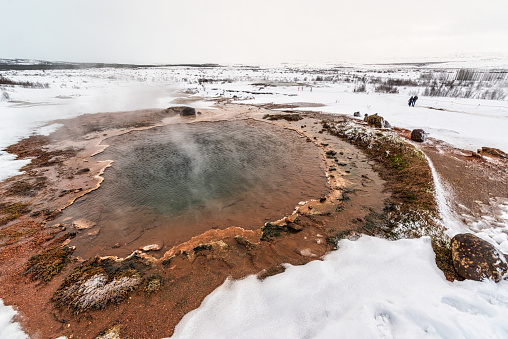 The Konungshver Geyser, part of Haukadalur, the home of geysers and other geothermal features along the Golden Circle tourist route in southern Iceland on a foggy winter afternoon