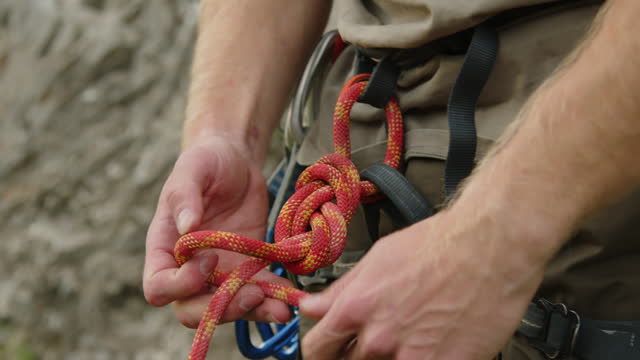 Hands of Mountain Climber Tying Rope to Belt