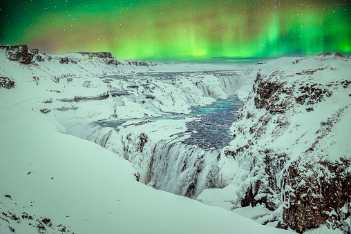 Snowy landscape at night at Gullfoss Falls with Northern Lights in Iceland during winter. Golden circle route