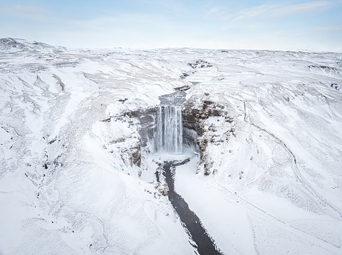 Aerial drone view of Skogafoss Waterfall in Iceland a Beautiful Landmark Covered in Snow in winter against blue sky