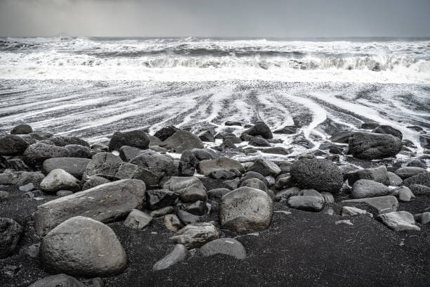 close-up of black rocks at in dangerous  Rynisfjara Black Sand Beach in a stormy day, Vik, Iceland