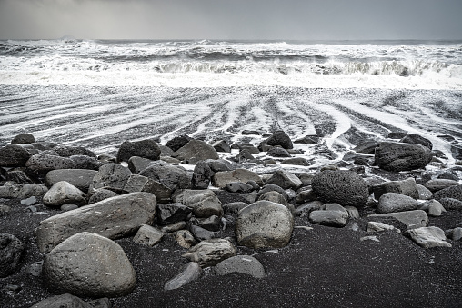 close-up of black rocks at in dangerous  Rynisfjara Black Sand Beach in a stormy day, Vik, Iceland