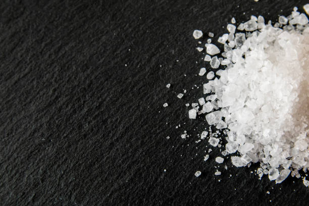 istock White salt cristals for food on the black background. 2064009317