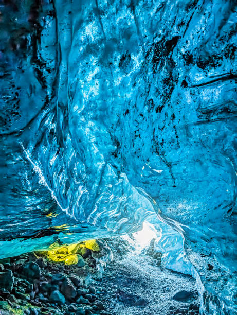 Explorer stands in mouth of ice cave at night, British Columbia