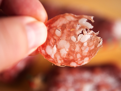 Close-Up of a Hand Holding a Slice of Salami