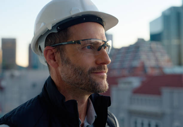 Happy man, architect and thinking with helmet in city for construction, industrial design or architecture. Male person, contractor or engineer with safety equipment for construction in an urban town