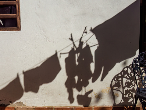 The shadow of clothes hanging drying casted on a wall by the morning sunlight, in a house near the town of Arcabuco, in central Colombia.