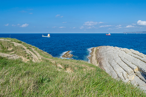 Green, rocky coast of Santander, Cantabria, northern Spain, with boats in the background