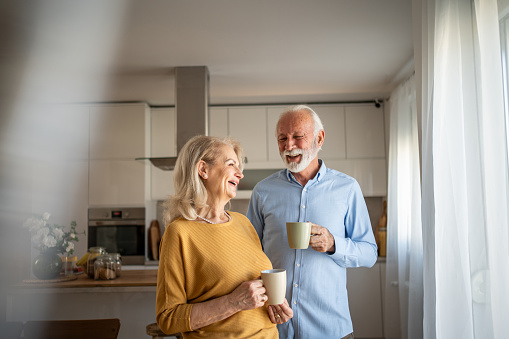 Cheerful elderly couple enjoying life and long-term love together with morning coffee