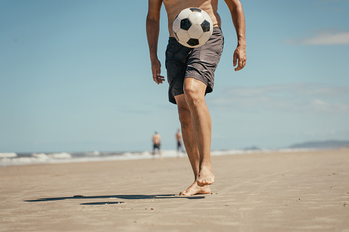 Man kicking soccer ball on the beach