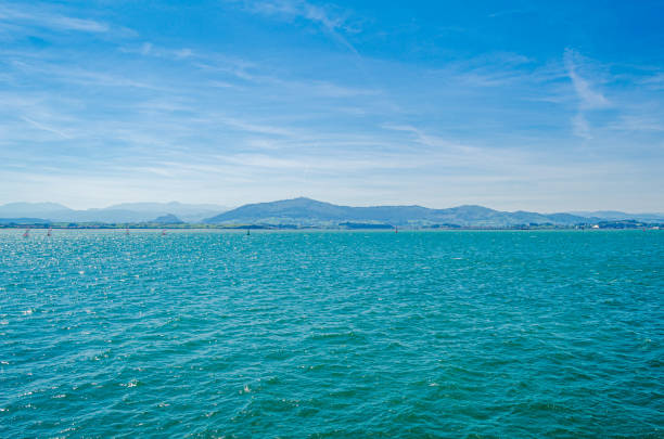 Horizontal high angle landscape of the rippled blue ocean of the bay and distant hills, mountain ranges and Mt Warning or Wollumbin, in the far distance.