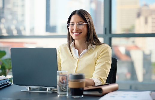 Woman, laptop and office with documents, smile and technology for working and planning. Web designer, computer and workspace for business, research or communication for target or goals with paperwork