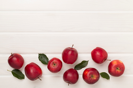 Fresh red apples with leaves on wooden background, top view