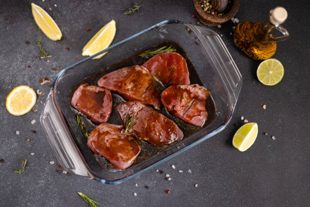 marinierte stücke von frischem thunfisch fischfilet in glaskochschale auf einem küchentisch - raw tuna steak marinated sauces stock-fotos und bilder