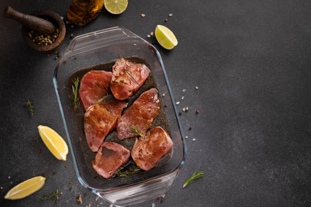 marinierte stücke von frischem thunfisch fischfilet in glaskochschale auf einem küchentisch - raw tuna steak marinated sauces stock-fotos und bilder