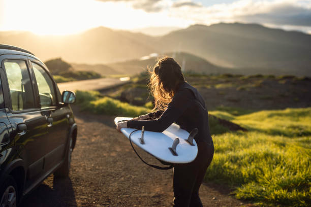 Surfing after work at sunset. Surfer girl gets ready to surf.